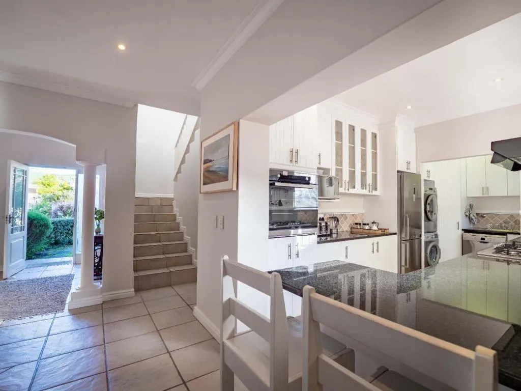 Tiled entrance hall with a staircase leading up, opening onto a white fitted kitchen