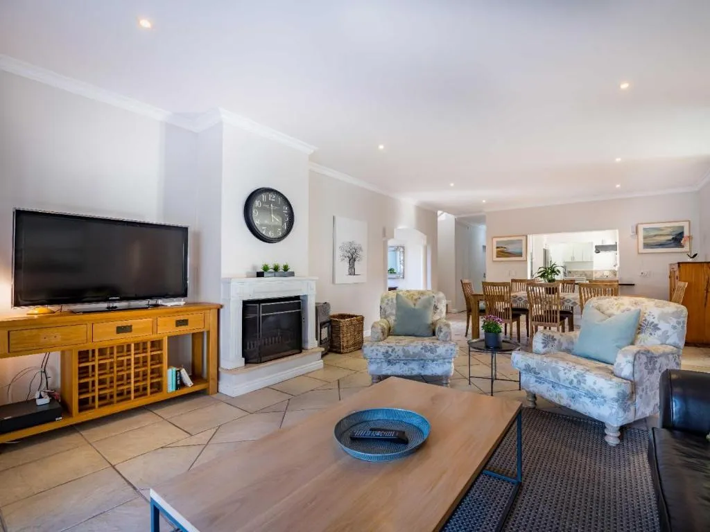 Open-plan living room with a fireplace, TV console and a dining table visible beyond