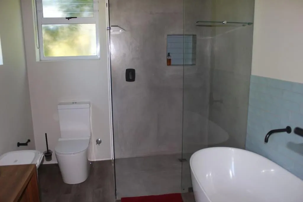 Bathroom with a glass-walled shower and a freestanding tub against blue tiles