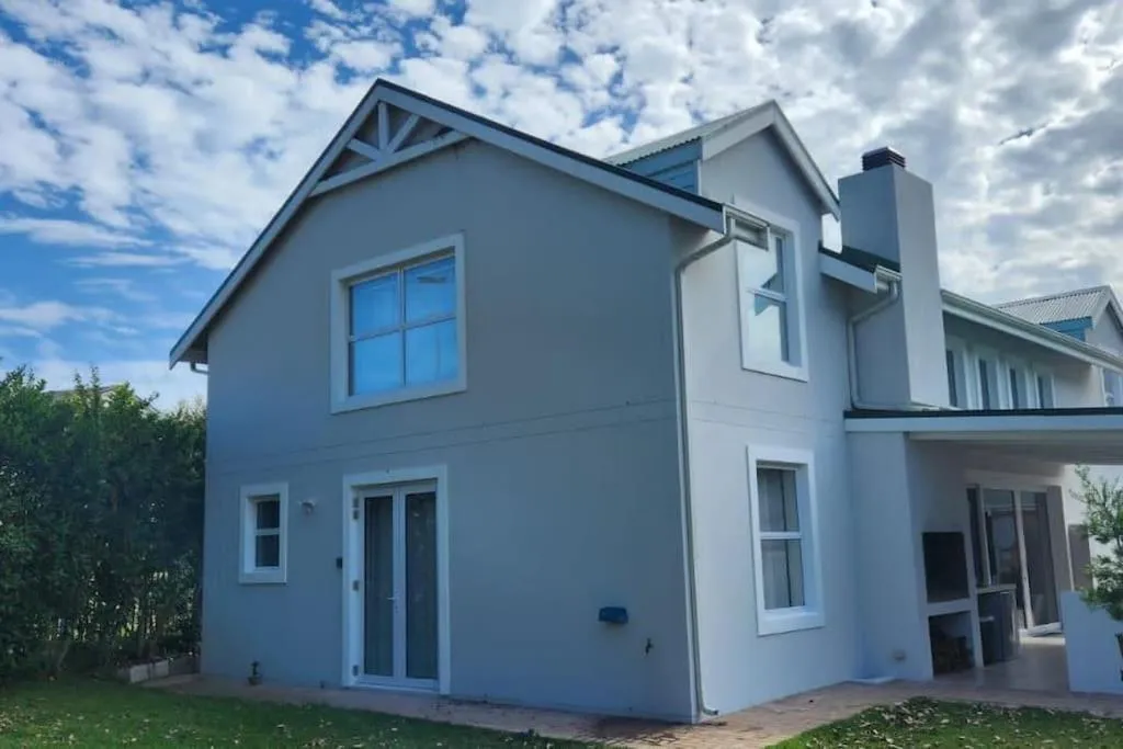 Double-storey gabled house exterior with a chimney and covered ground-floor patio