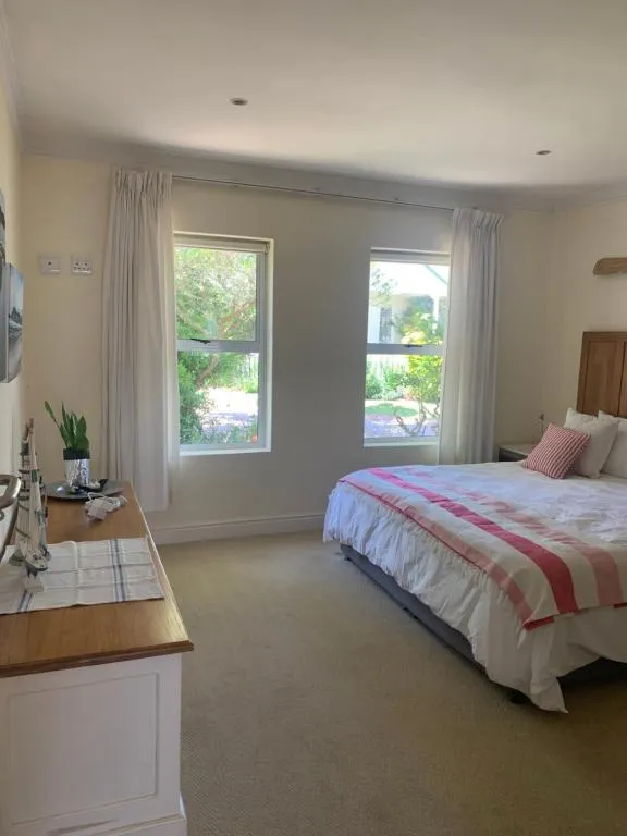 Bedroom with twin sash windows looking onto a leafy garden and neighbouring rooftops