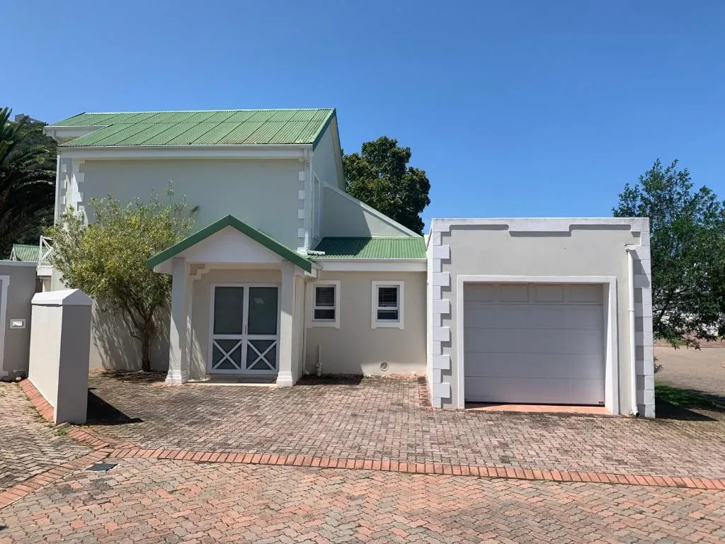Freestanding house exterior with a green corrugated roof, garage and paved driveway