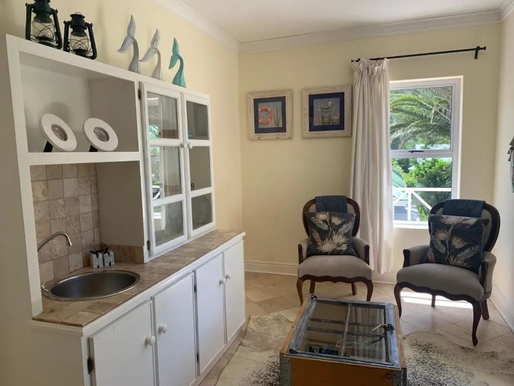 Living room corner with a white wooden hutch, wet-bar sink and upholstered armchairs
