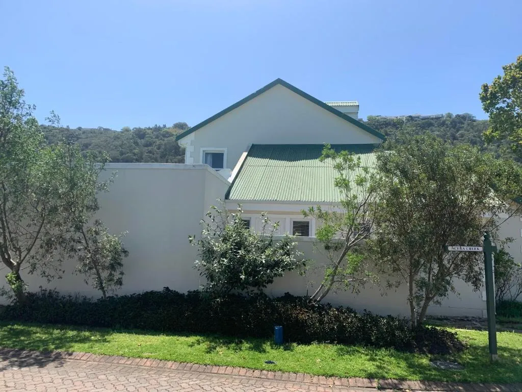 House exterior seen from the street, with a green roof and garden wall along Ncera Creek