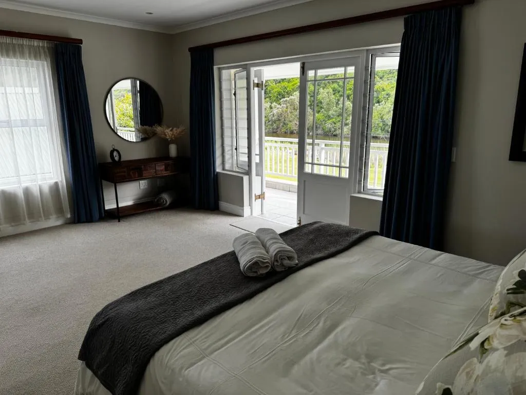 Bedroom with French doors opening onto a balcony overlooking the river and lawn