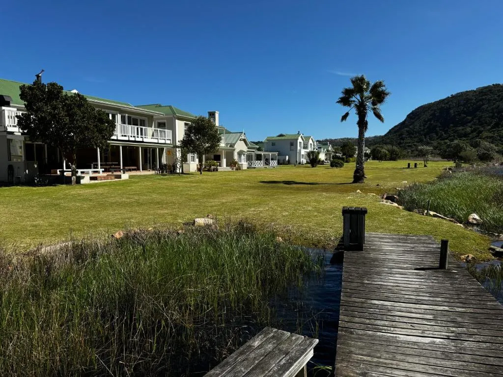 Communal lawn with a wooden jetty over the river, backed by a forested mountain