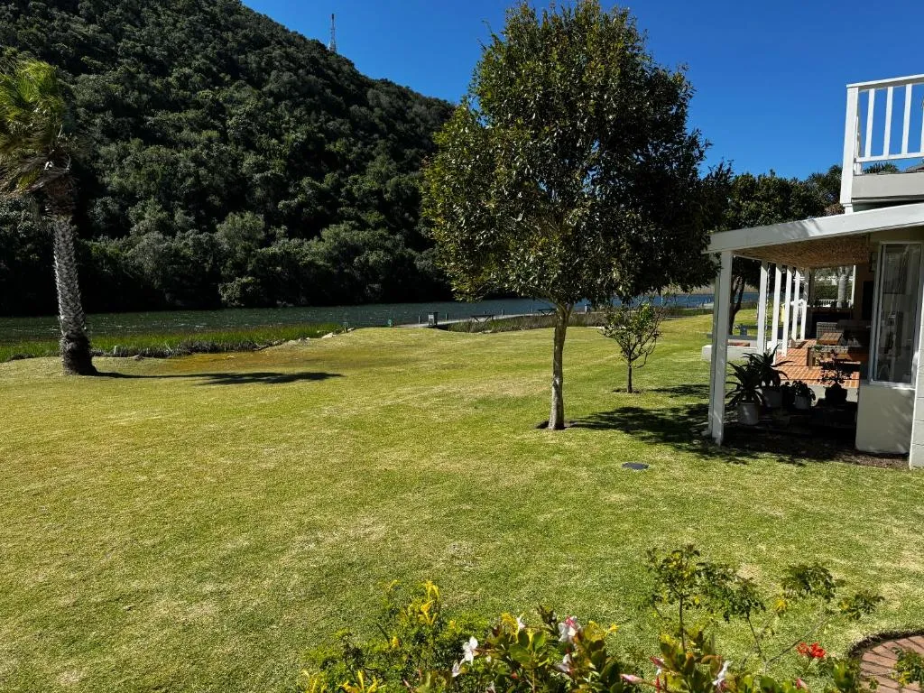 Garden lawn running down to the river's edge with a mountain backdrop