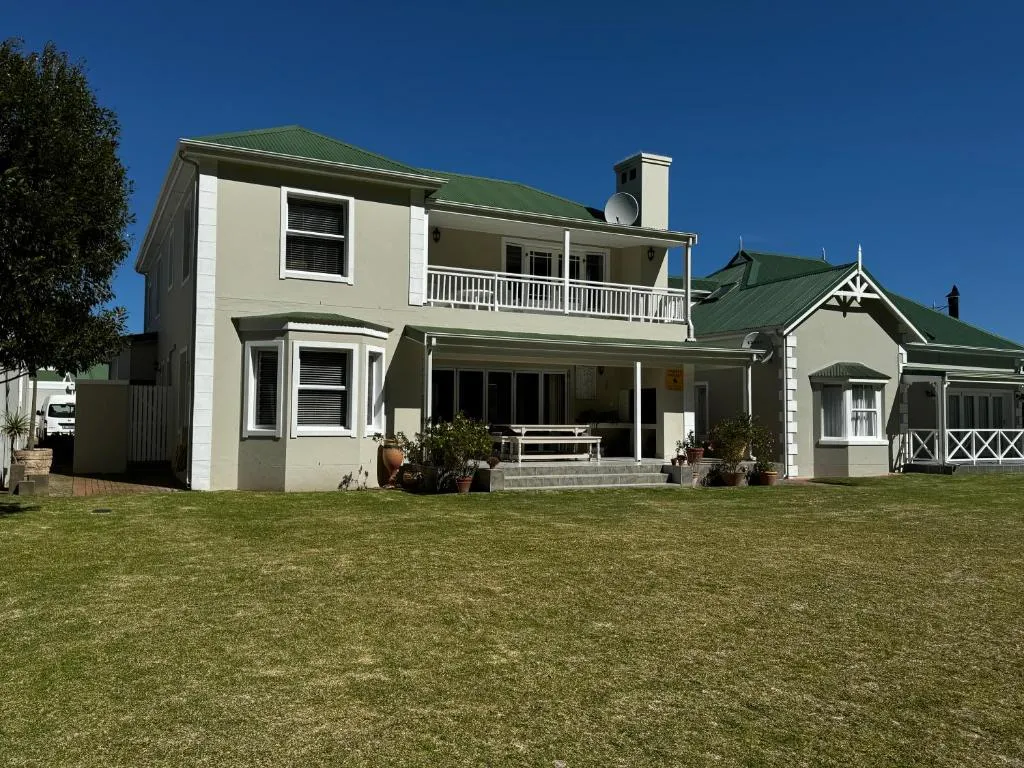 Rear facade of the double-storey home with green roof and covered balcony above the patio