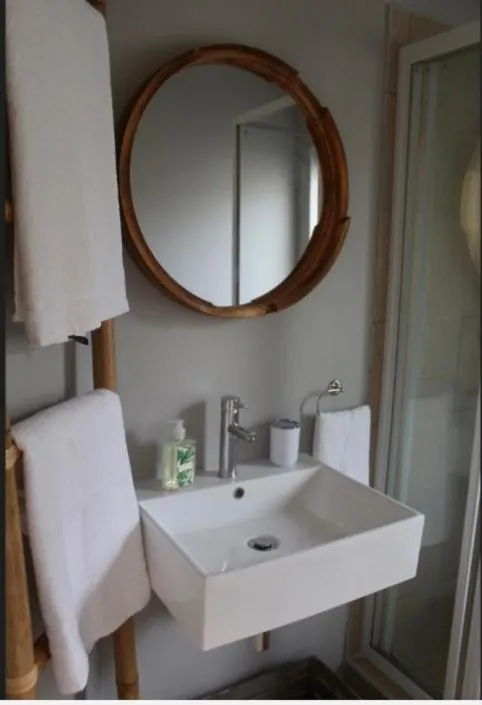 Bathroom with a round bamboo-framed mirror over a wall-mounted basin