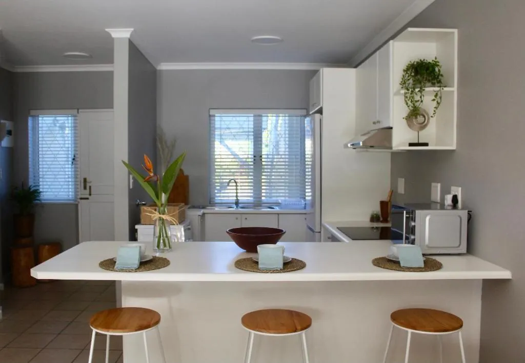 Kitchen breakfast bar with three wooden stools and place settings for guests