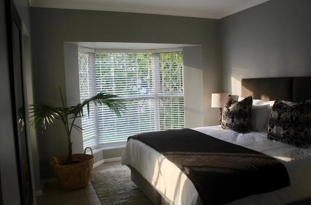Bedroom with a bay window seat, dark upholstered headboard and a potted palm