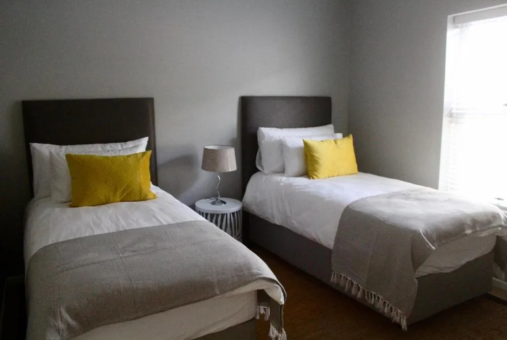 Twin bedroom with grey upholstered headboards and mustard yellow cushions