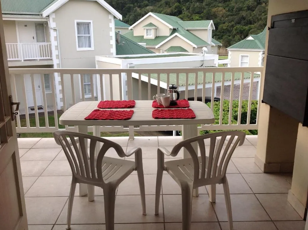 Balcony with table set for two, overlooking rooftops and a forested hillside