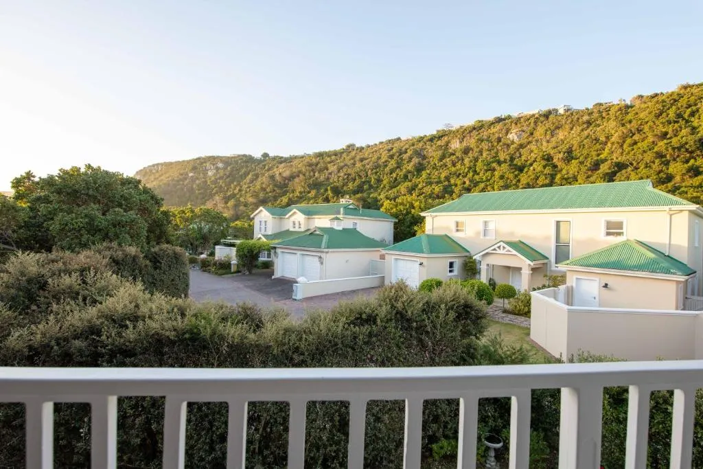 Balcony view over the villa complex towards a green, forested hillside