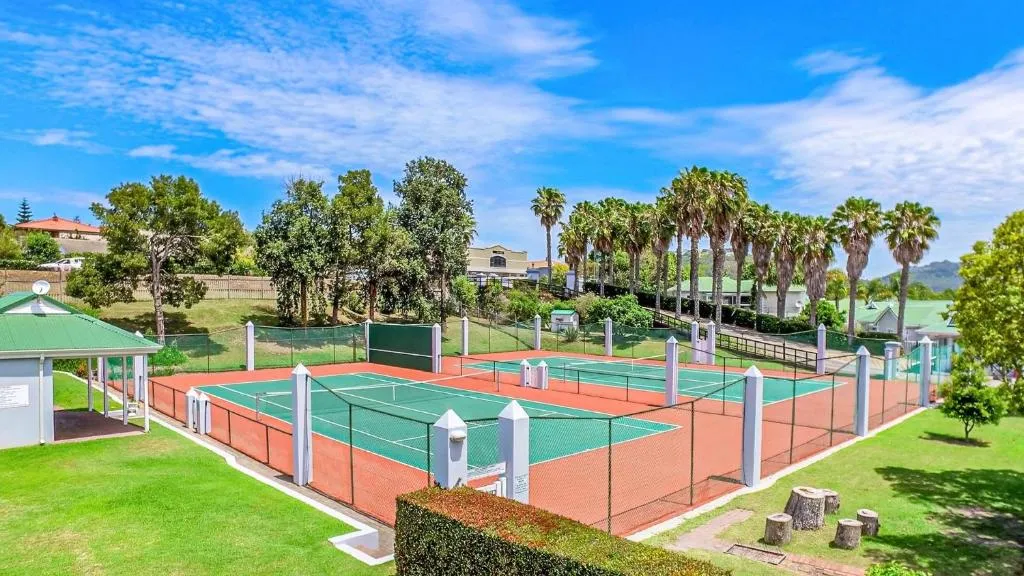 Aerial view of the estate's tennis courts framed by tall palm trees