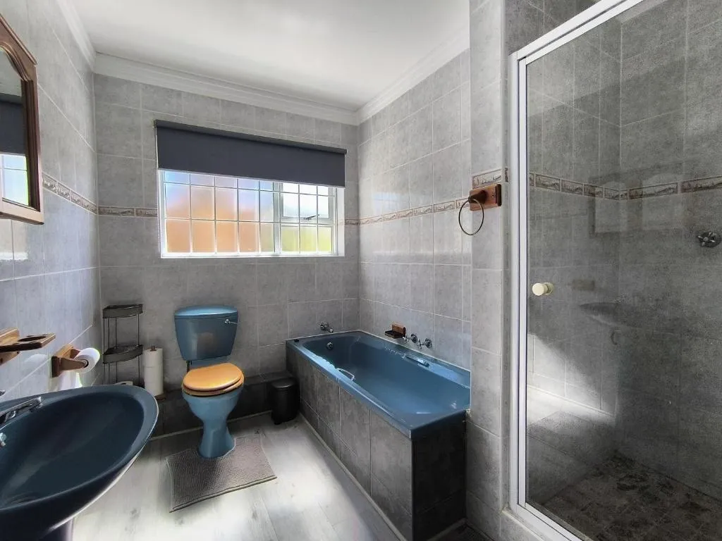 Bathroom with a blue enamel bath, matching toilet, pedestal-style sink and separate glass shower