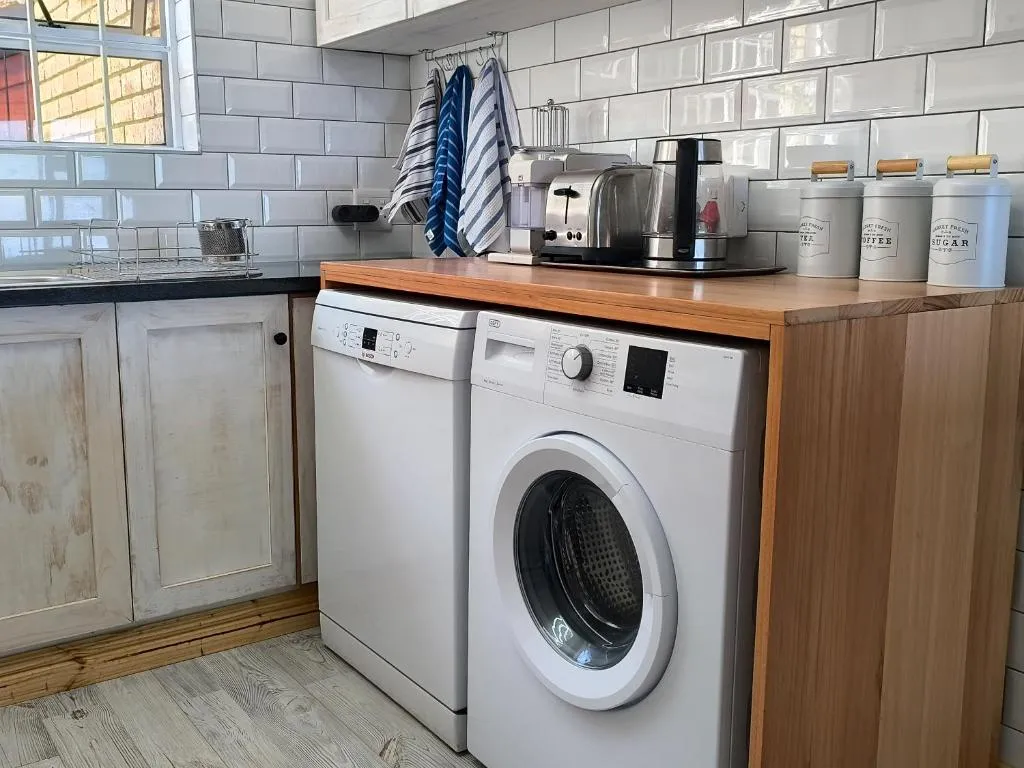 Laundry nook with a washing machine and tumble dryer beneath a wooden countertop and subway tile