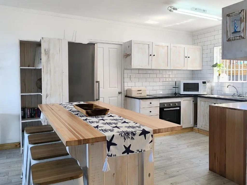 Kitchen with whitewashed reclaimed-wood cabinetry, subway tile splashback, a wooden breakfast bar and stools