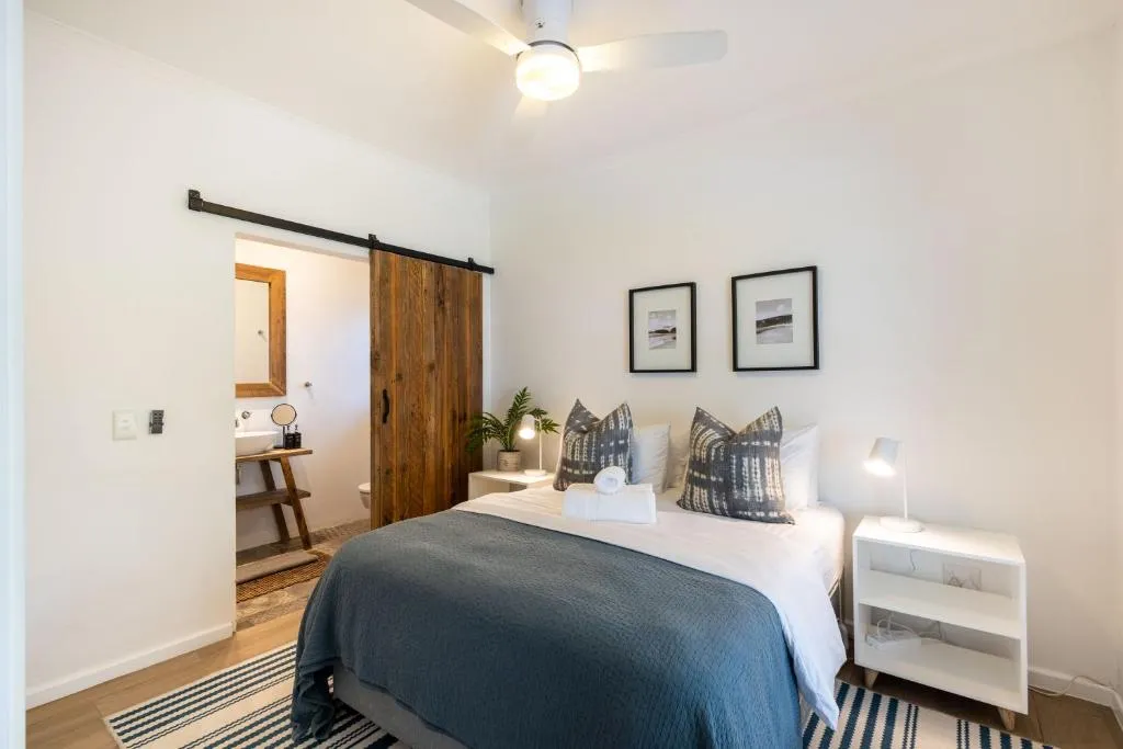 Bedroom with a sliding barn door onto an ensuite bathroom and a striped area rug