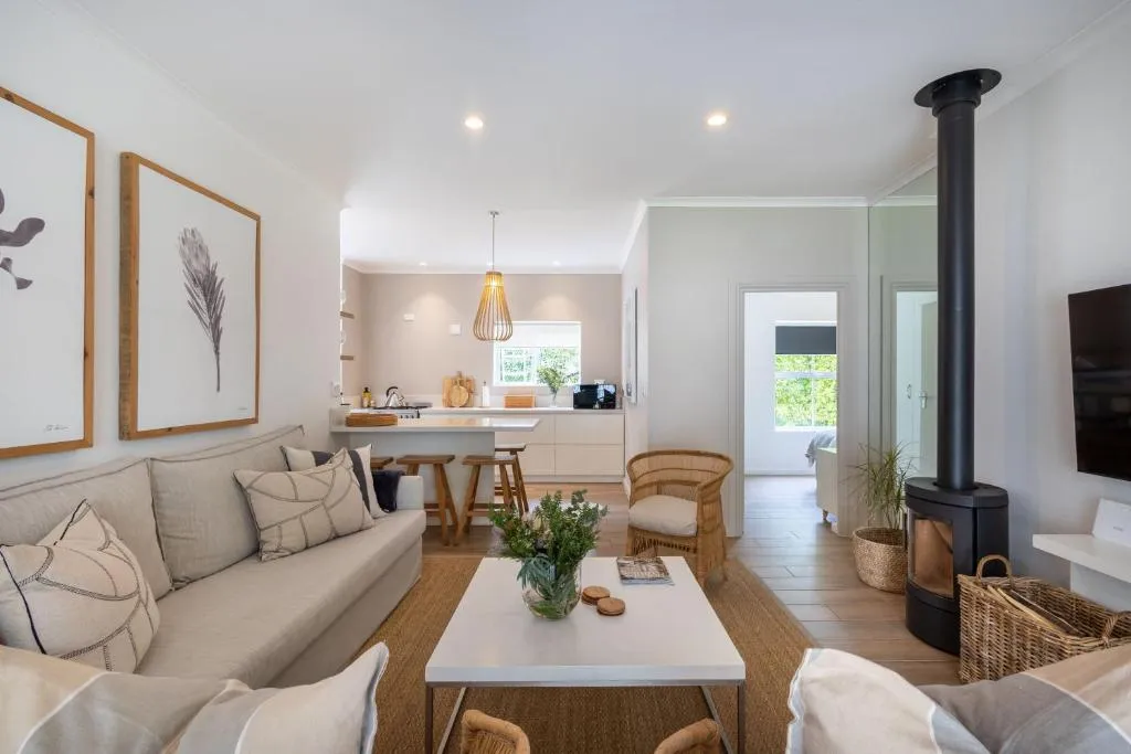 Living area with protea artwork, wood-burning stove and an open sightline to the kitchen