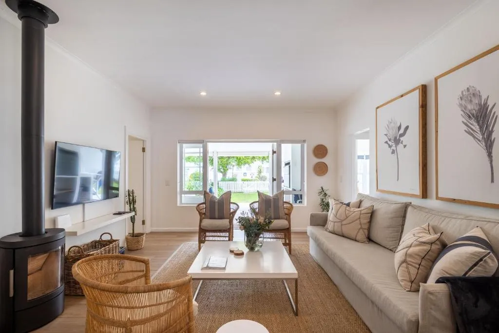 Living room with French doors open onto a lawned garden with a white picket fence