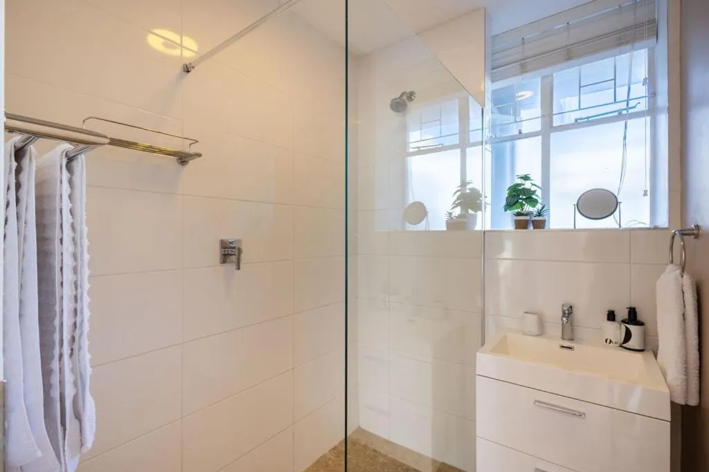 Bathroom with a glass-walled shower, window ledge, and a white vanity basin