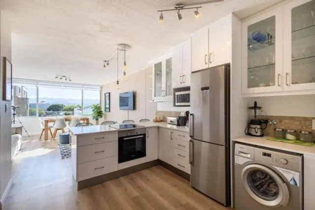 Kitchen with white cabinetry, a stainless fridge, built-in oven, and a front-loading washing machine
