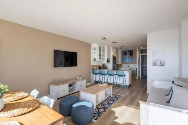 Open-plan living area with a breakfast bar, pouf seating, and a sofa corner