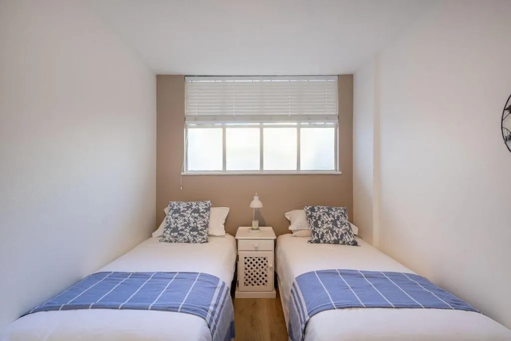 Twin bedroom with two single beds, blue-striped throws, and a shared bedside table