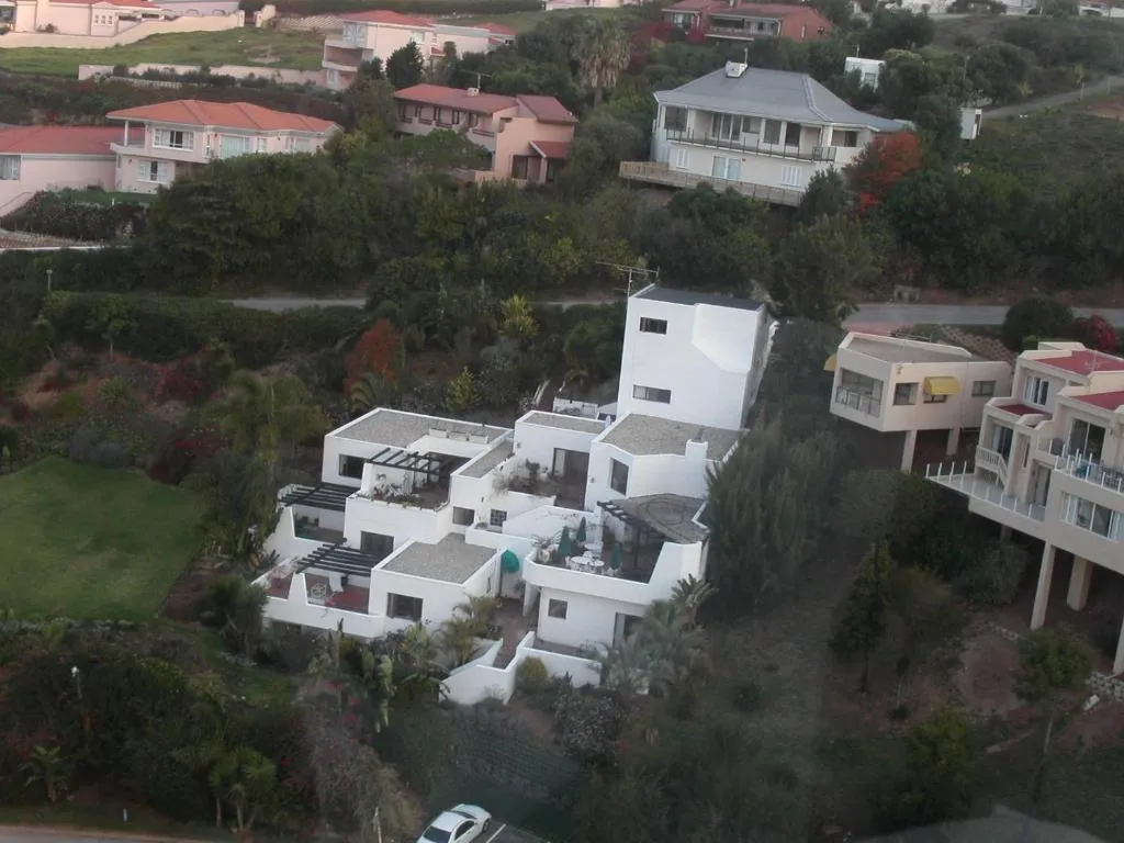 Aerial view of the white multi-level villa and its terraces amid Plettenberg Bay gardens