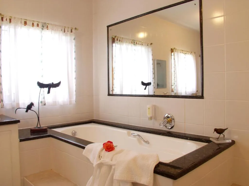 En-suite bathroom with a corner soaking tub, black-framed mirror and bird ornaments