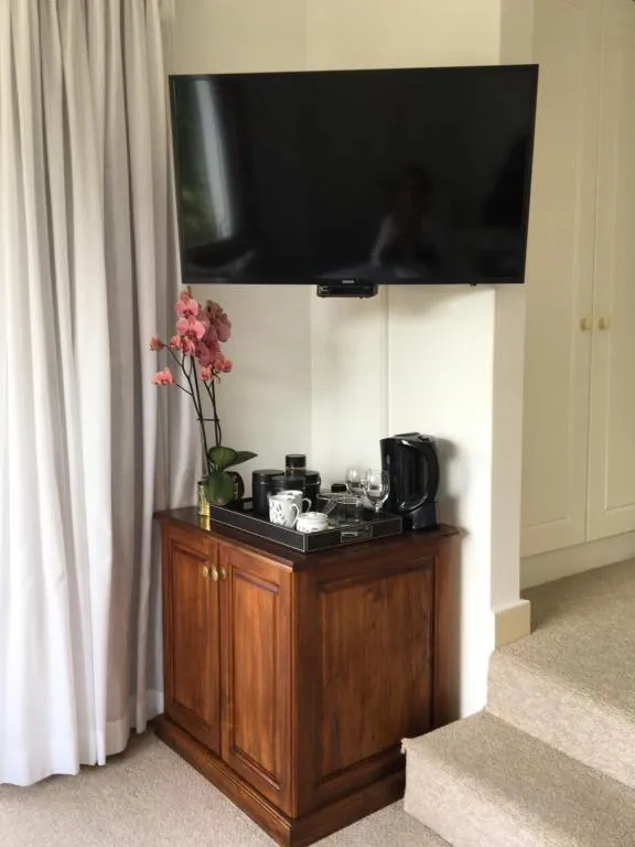 Bedroom corner with a wall-mounted TV and a wooden hospitality tray with kettle and cups