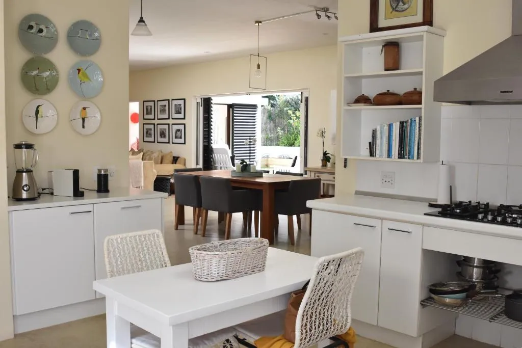 Open-plan kitchen with gas hob and dining table, opening through folding doors to the garden
