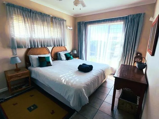 Bedroom with wicker headboards, twin bedside lamps and sliding doors onto a balcony
