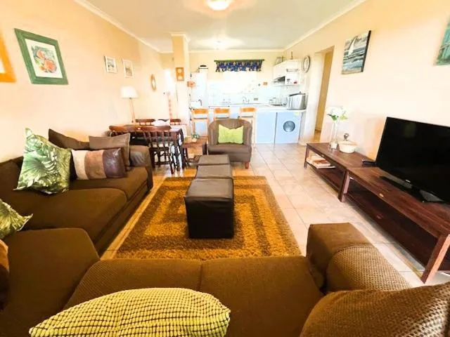 Living room with a brown sectional couch, coffee-table ottomans and a wall-mounted TV