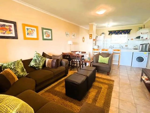 Open-plan kitchen with dining table, breakfast bar stools and a front-loader washing machine