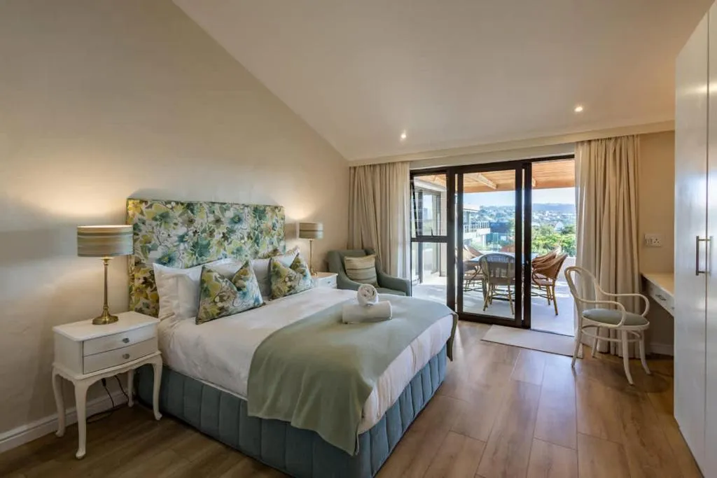 Bedroom with a floral headboard and sliding doors onto a private balcony over the town