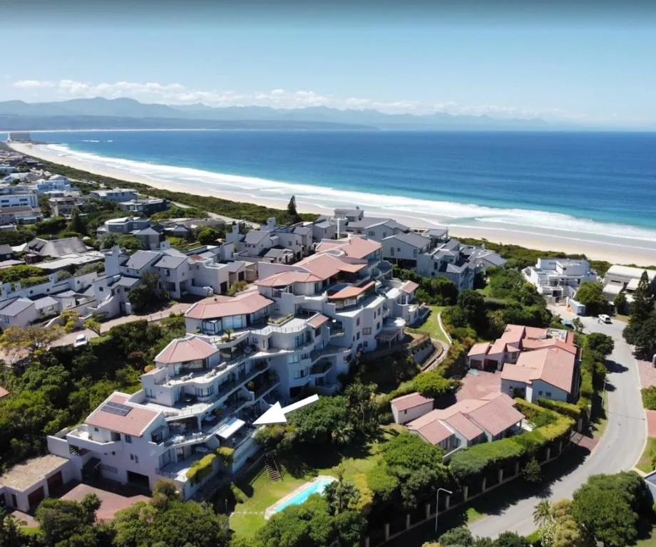 Aerial view of the whitewashed beachfront apartment complex with the unit marked, steps from the sand