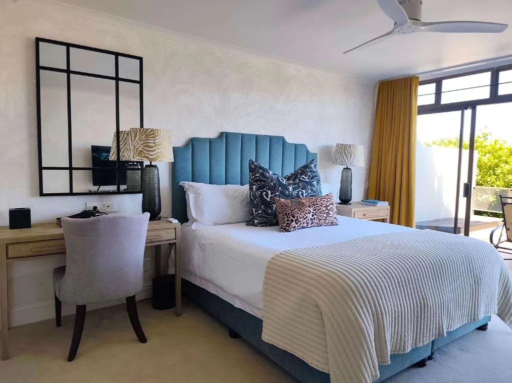 Bedroom with a teal channel-tufted headboard, mustard curtains and doors onto a private balcony