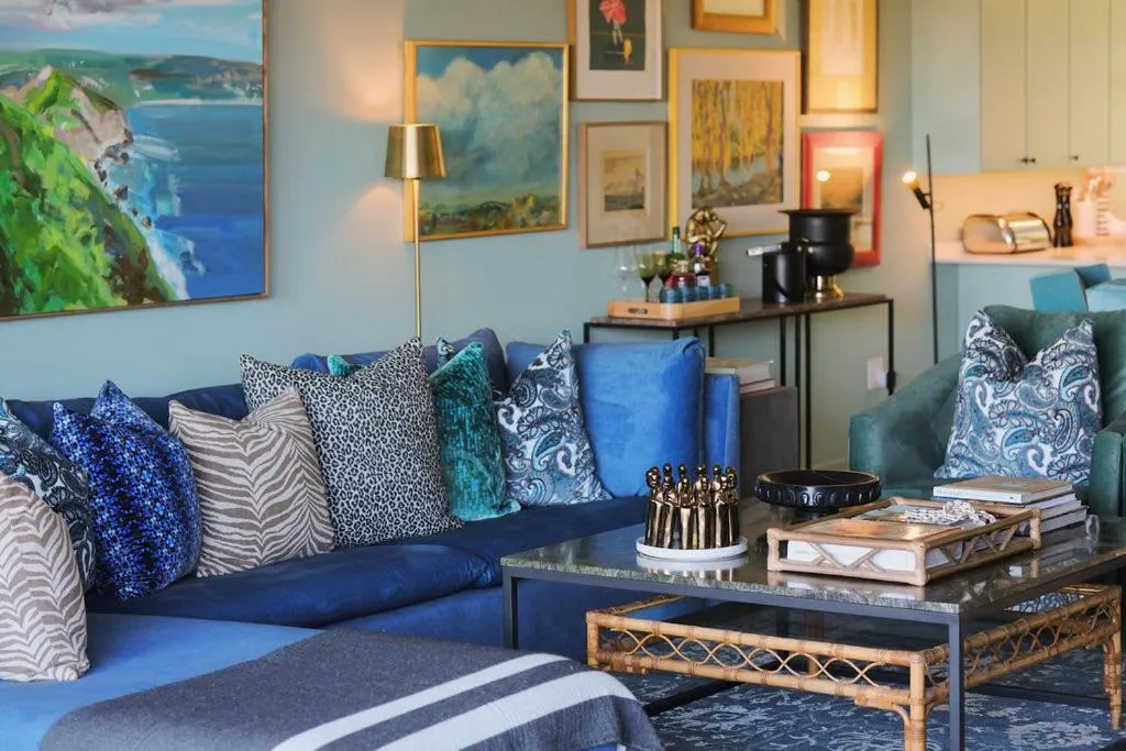 Living room with a navy velvet corner sofa, patterned cushions and gallery-hung artwork