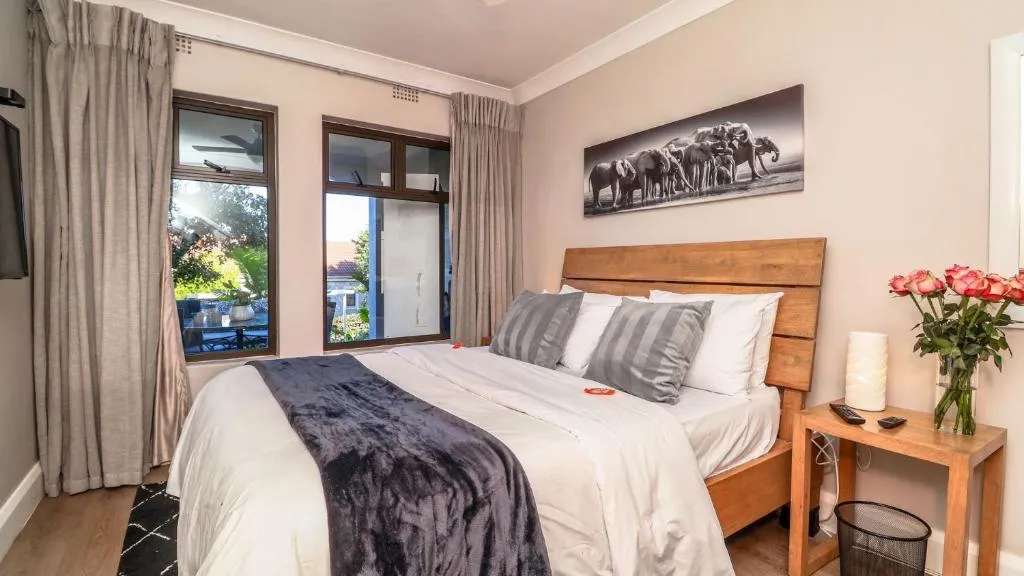 Bedroom with twin windows onto a courtyard, matching elephant print artwork and a fresh rose posy