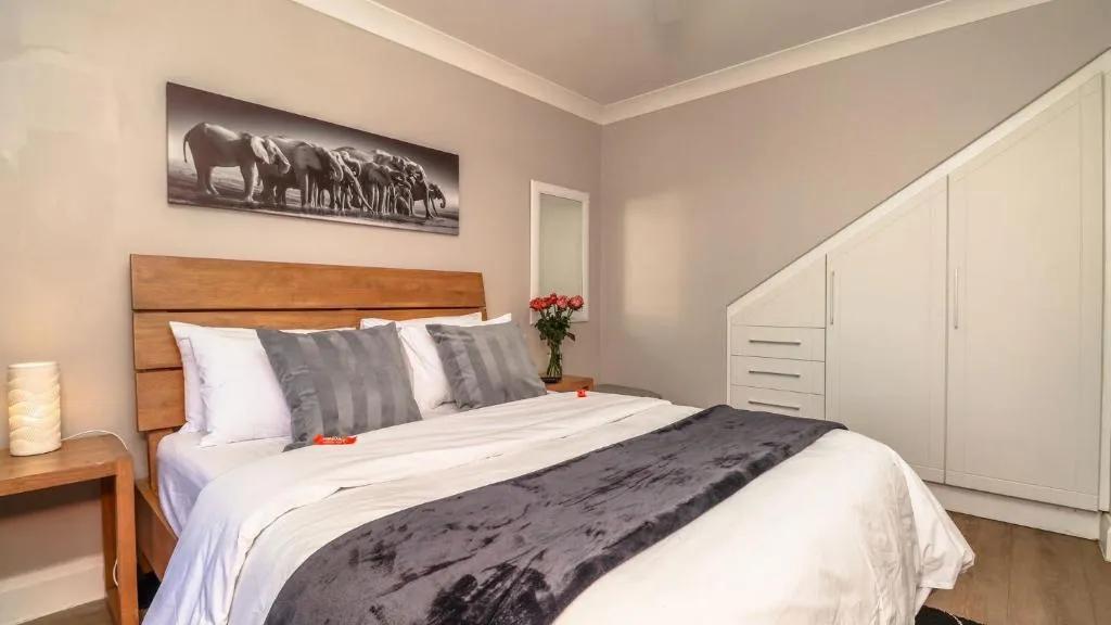 Bedroom with a wood-panel headboard, elephant herd canvas print and a built-in sloped-ceiling wardrobe