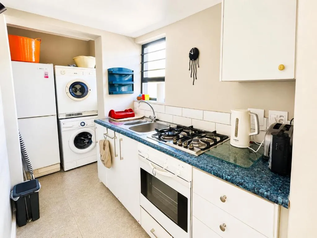 Galley kitchen with a gas hob, built-in oven, and a stacked washer-dryer unit