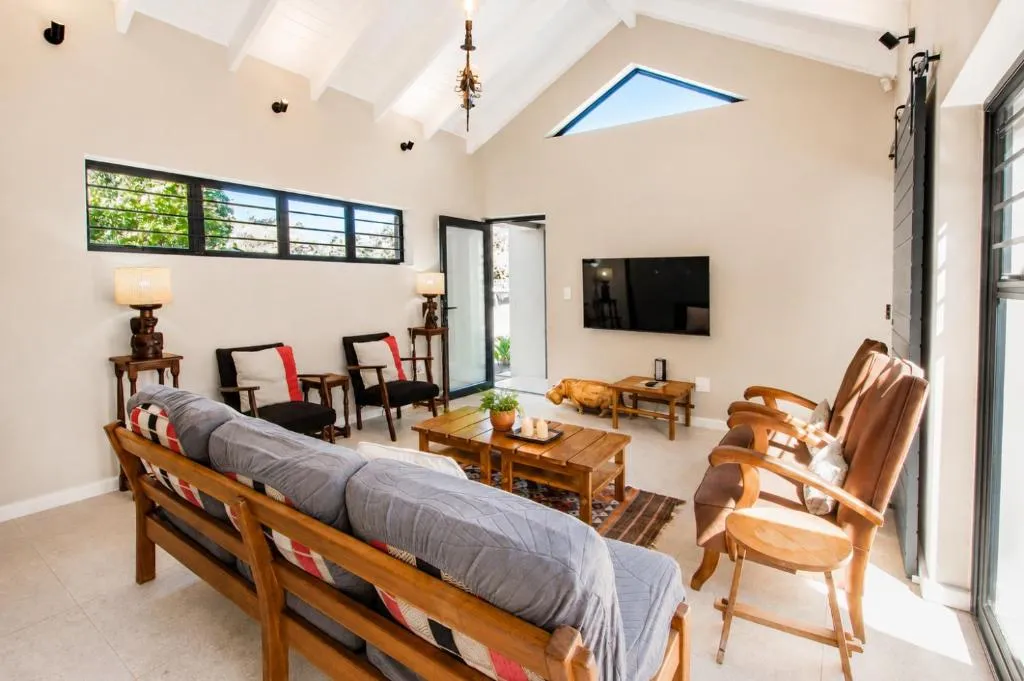 Second view of the vaulted living room showing the sofa back, side chairs, and skylight window