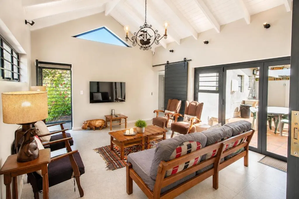 Vaulted-ceiling living room with a grey sofa, wooden armchairs, and a barn-style sliding door