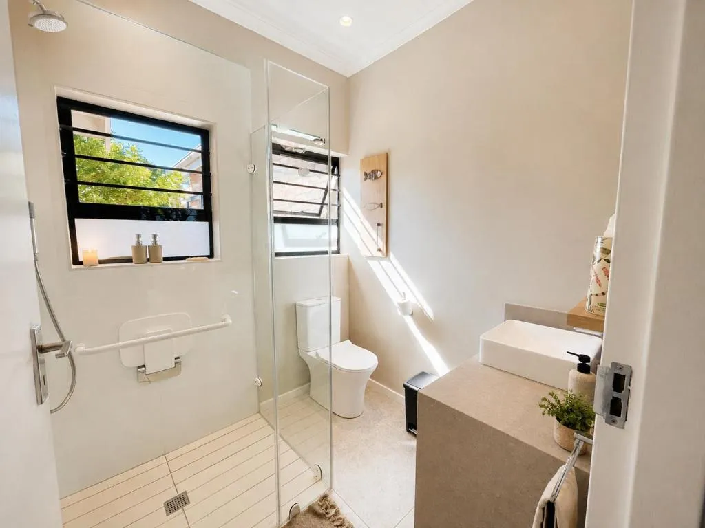Accessible bathroom with a grab-rail shower, tiled walls and a garden-facing window
