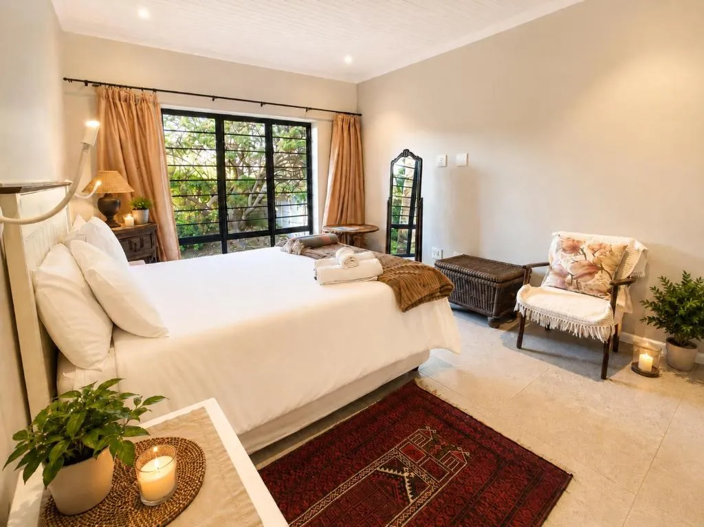 Bedroom with cream bedding, floral curtains and a window looking onto the garden