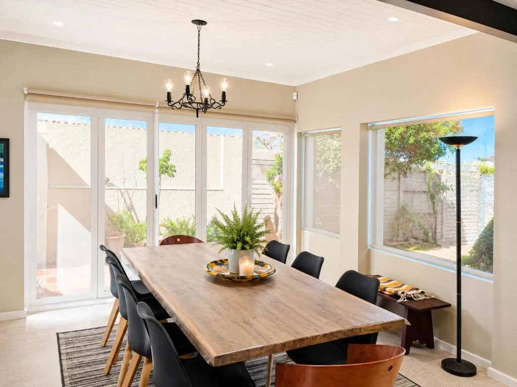 Dining room seating eight at a wooden table, glass doors opening onto the garden