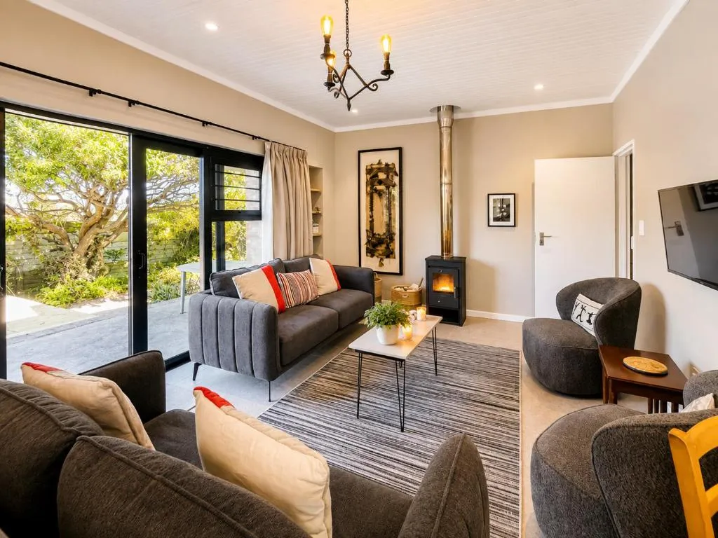 Living room with wood-burning stove and grey sofas opening onto the garden through glass doors