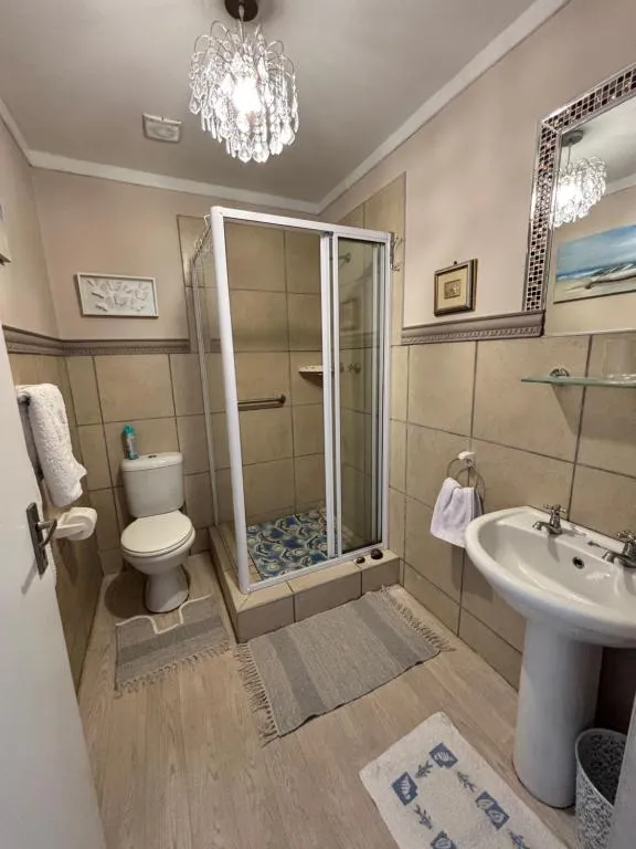 Bathroom with a glass shower cubicle, pedestal basin and mosaic-framed mirror